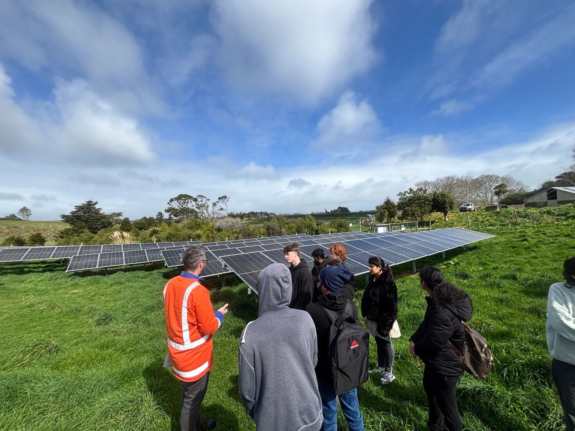 A group of people beside solar panels at Waiuku Solar Farm