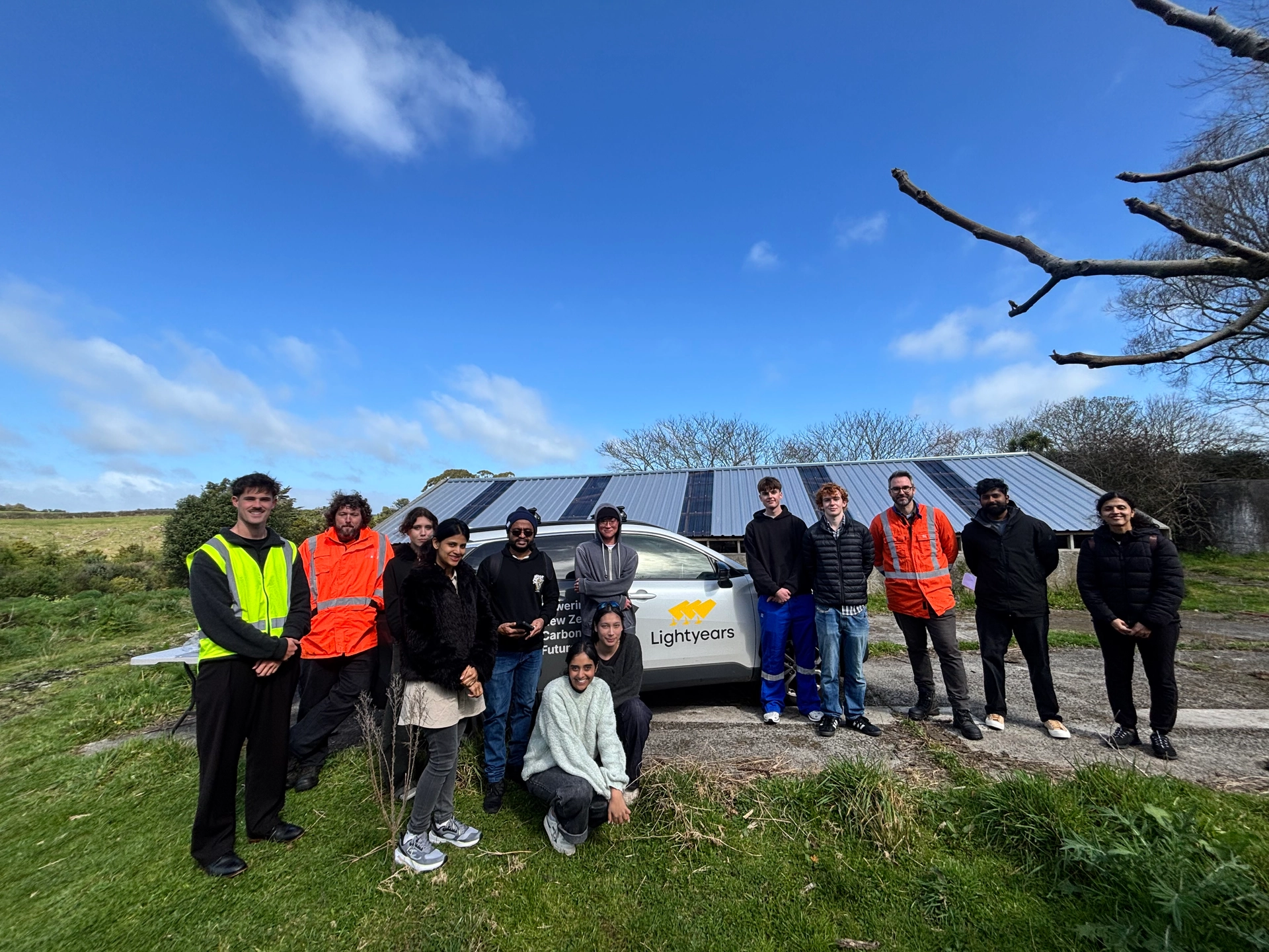 A group standing beside a Lightyears vehicle and solar panels