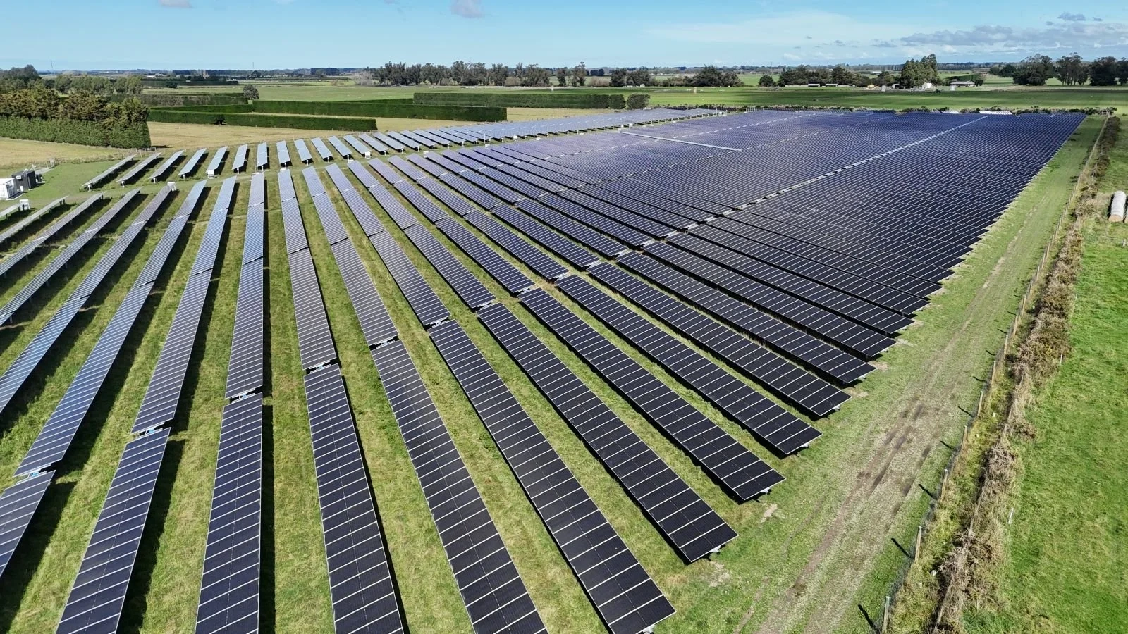 Aerial view of rows of solar panels across a rural site